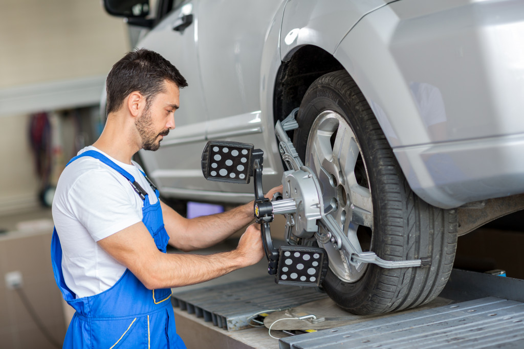 A young car mechanic fixing a car's tire in his workshop