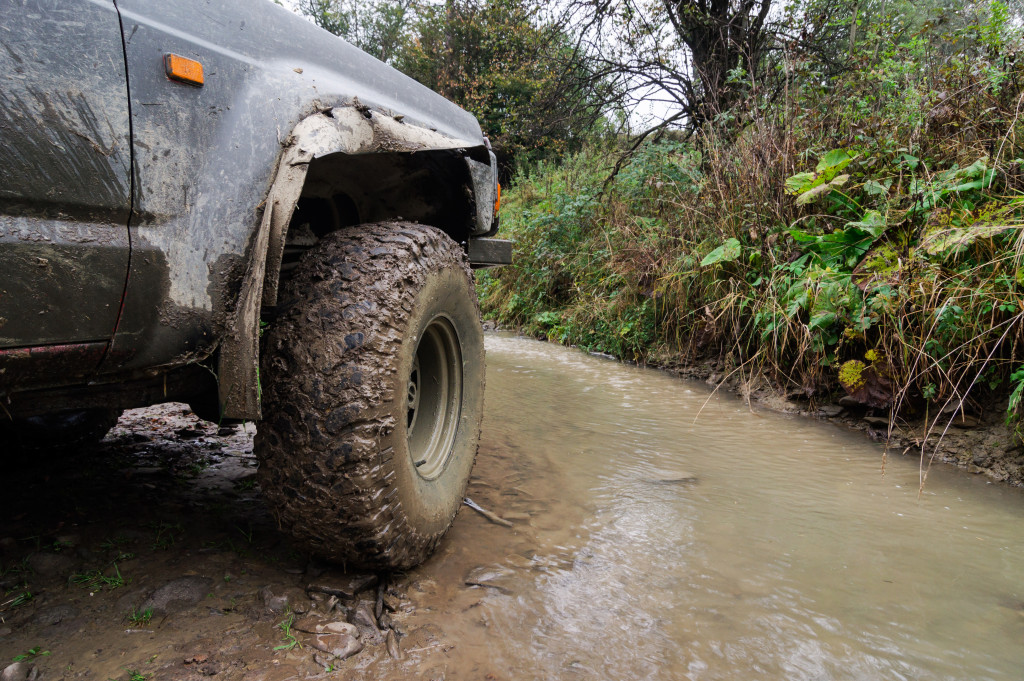 A dirty truck driving at the side of a river