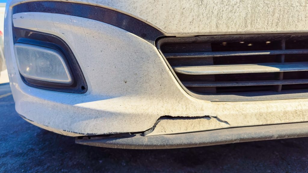 close-up of damage on a white car's bumper