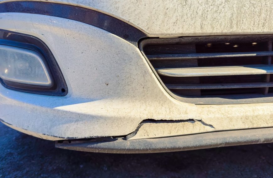 close-up of damage on a white car's bumper