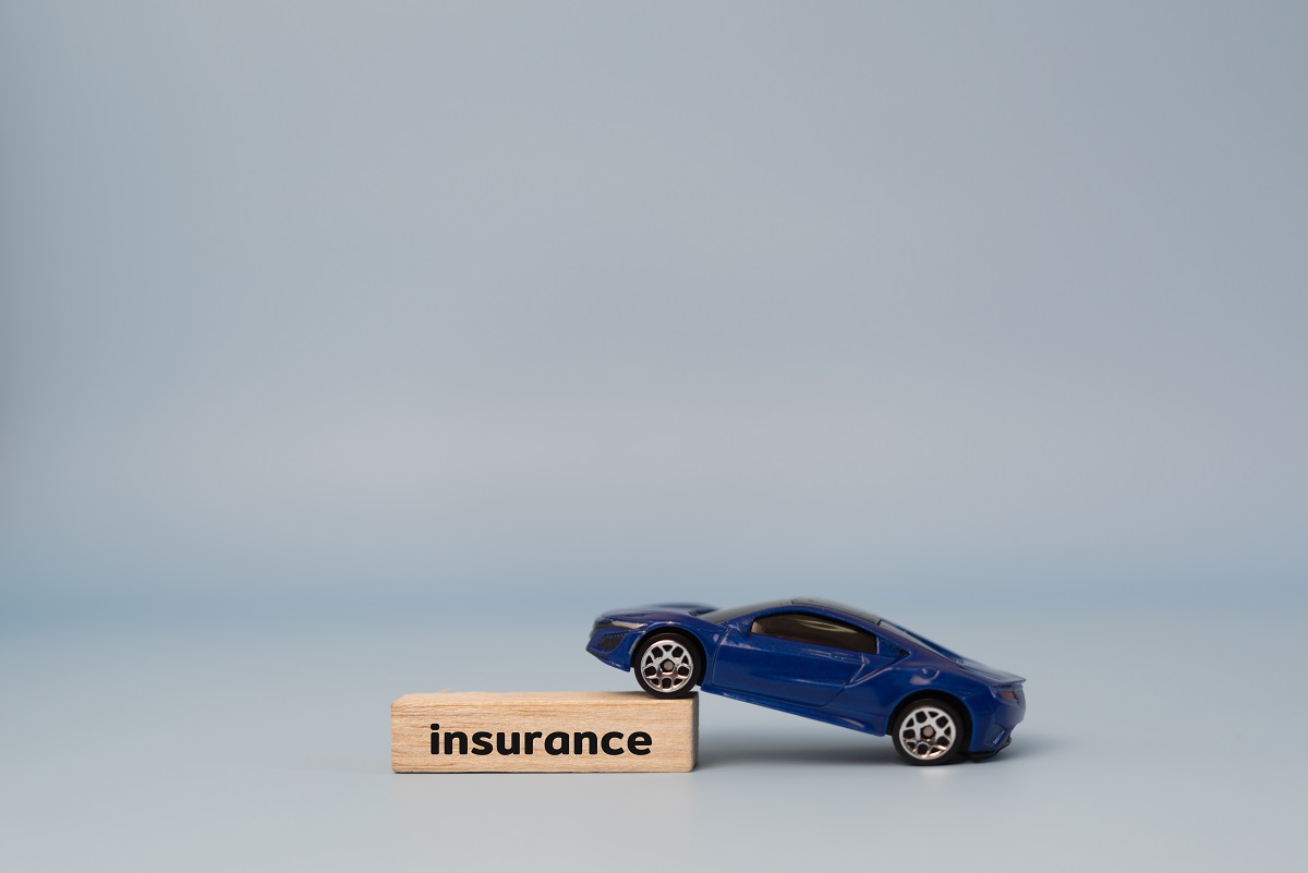 blue toy car resting on a wooden block labeled 'insurance'